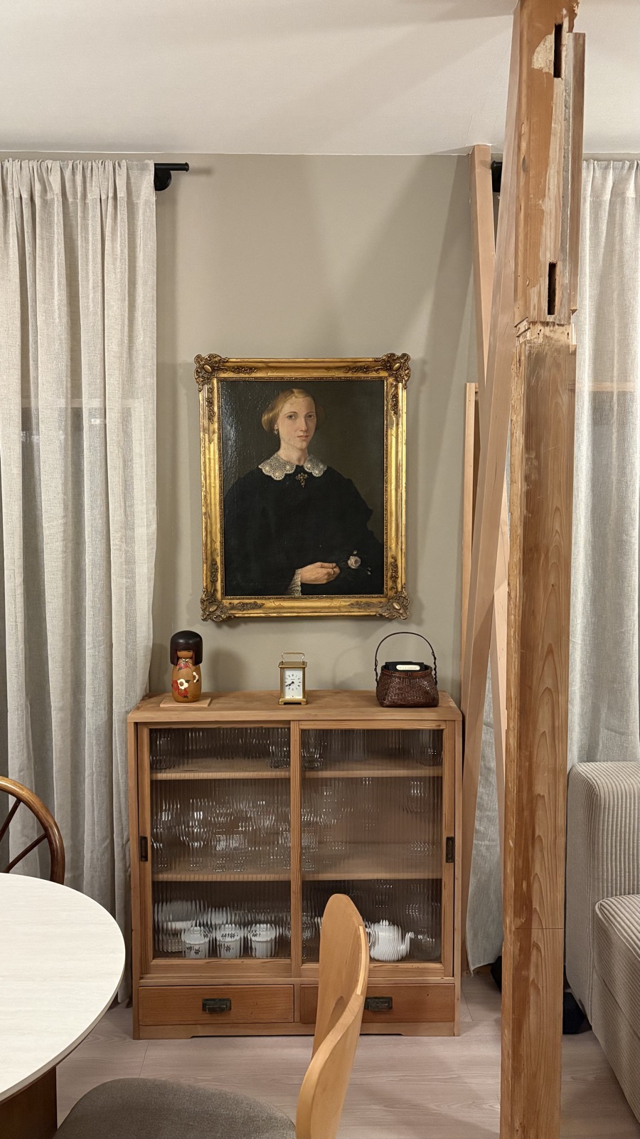 Dining area with antique portrait and vintage glass cabinet in restored akiya