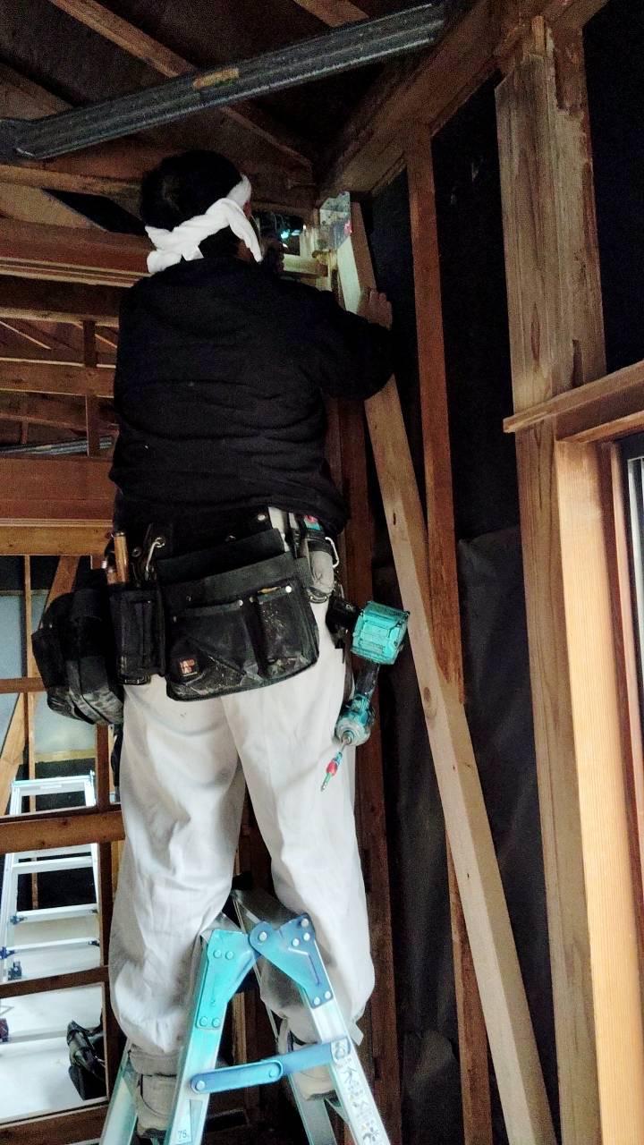 Close-up of the carpenter fitting reinforcement into the exposed wall frame